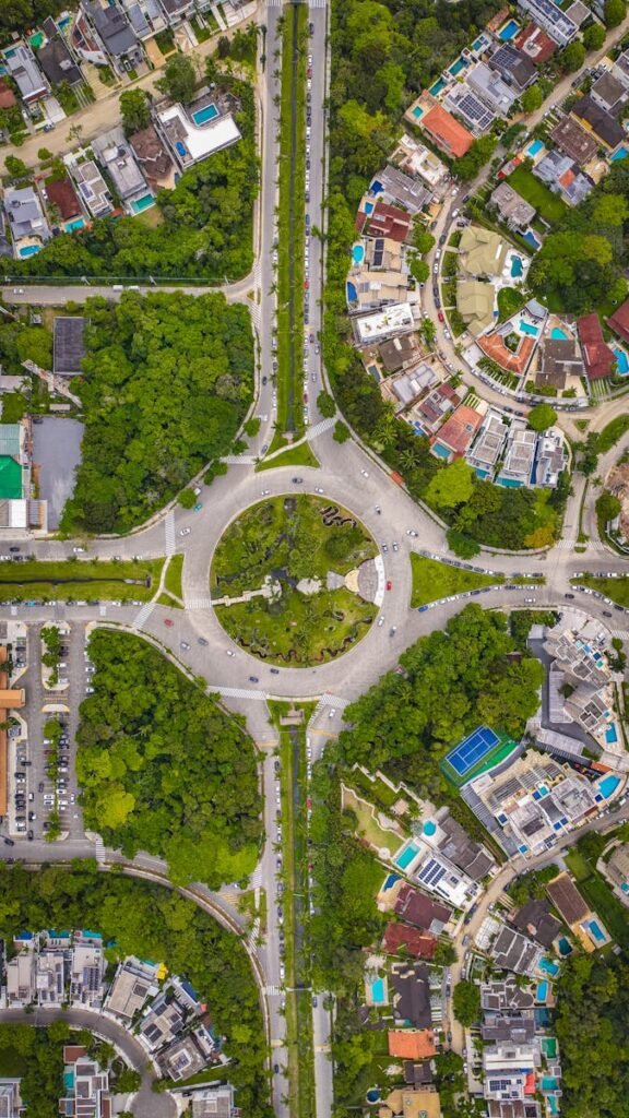 Capture of a bustling urban roundabout surrounded by greenery and residential buildings.